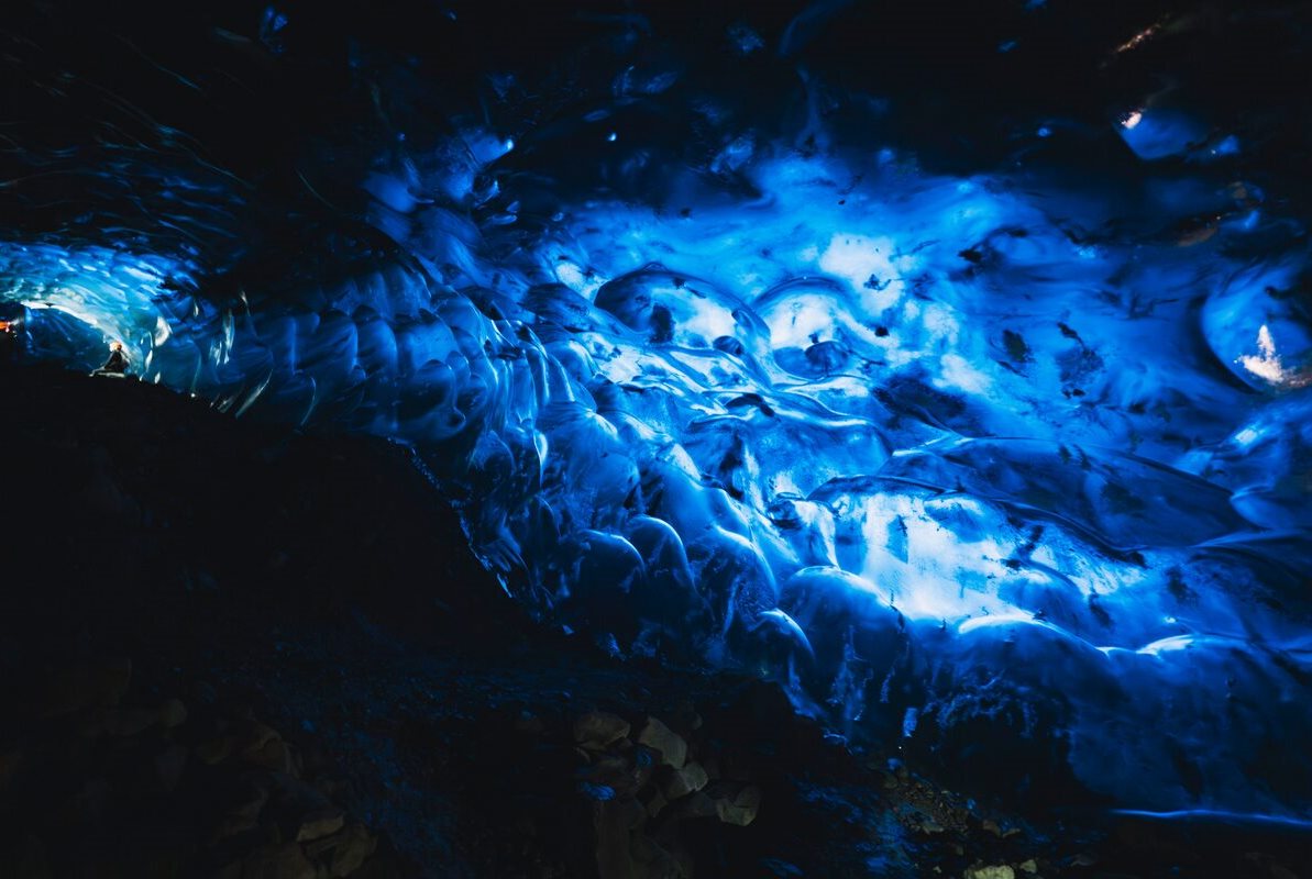 Posing in the entrance of the ice cave Tourists inside bright blue Crystal Cave on small group tour