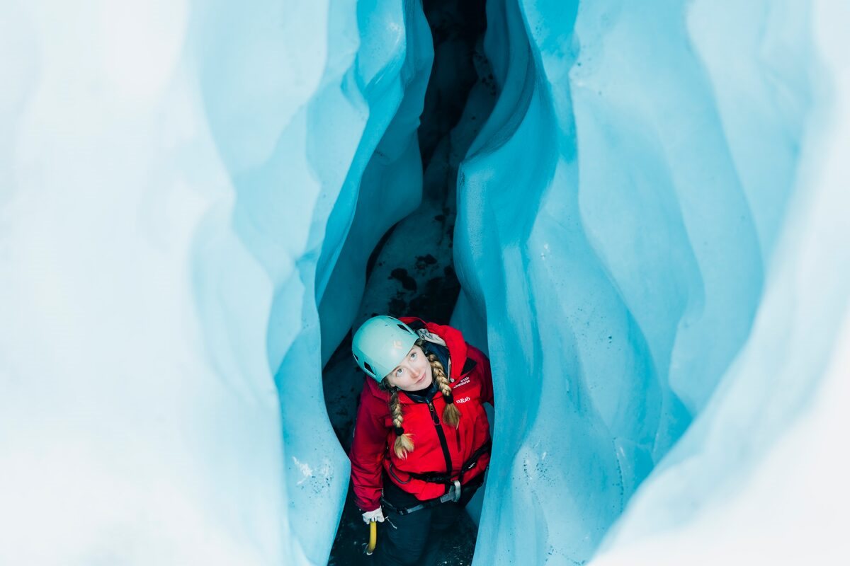 Ice Climbing and Blue Ice Crevasses Female tourist exploribng blue ice crevasse during ice climb.