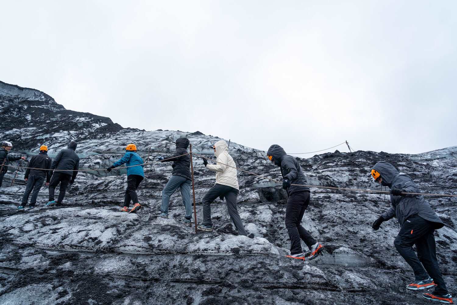 Tour group hiking on dark volcanic ash ice route 